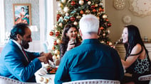 People gathered around a table in front of a Christmas tree, celebrating the holiday season together.