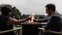 Two guests enjoying a drink beside a fire pit found on the grounds at Thoresby Hall Hotel