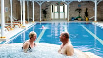 A couple of guests are having a laugh together in the bubble pool as another guest swims in the pool behind