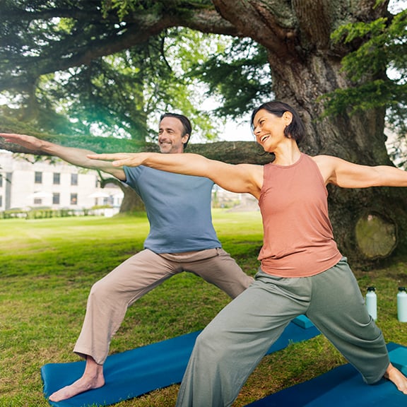 Mick and Angie smile as they try yoga outside Heythrop Park, a Warner Hotel